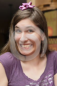 Young woman grinning with gift bow on her head