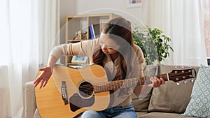 Young woman with guitar video blogging at home