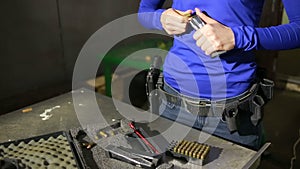 Young woman with the gun. indoor shooting range. charges cartridges in the gun