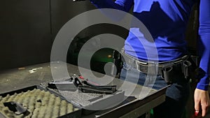 Young woman with the gun on an indoor shooting range. collect gun