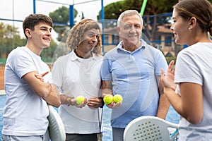 Four paddle tennis players talking on court