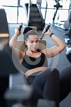 Young woman in gym doing crunches on machine