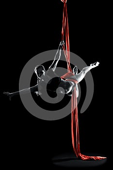 Young woman gymnast with red gymnastic aerial silks