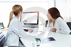 Young woman gynecologist doctor showing to patient some information in computer in medical consultation