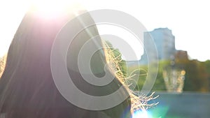 Young woman hair walking on urban street at summer sunny day. Lady enjoying breeze playing with her hair. Girl stepping