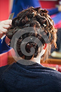 Young woman at hairdresser curling hair