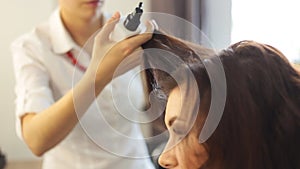 Young woman and hairdresser with hair iron making hairdo at hair salon