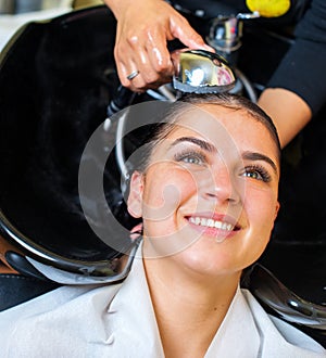Young woman with hairdresser washing head at hair salon