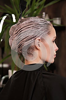 Young woman in a hairdressing salon dyes her hair blond and washing head