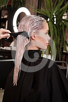 Young woman in a hairdressing salon dyes her hair blond and washing head