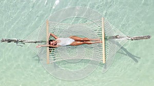 Young woman in hammock enjoying tropical vacations in the Maldive Islands. People travel relaxation. Girl relax on