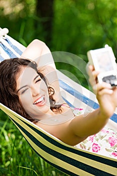 Young woman in a hammock in garden doing snapshot. photo