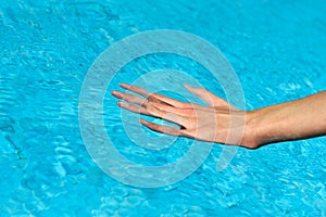 Young woman hand in blue water in a swimming pool horizontal