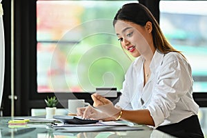 Young woman hand calculating expenses and debt from credit cards on office desk. E-commerce, financial planning and