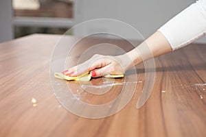 Young woman hand cleaning modern wood table by dust cloth, cleaning concept