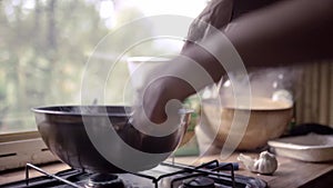A young woman hand is cooking in a gas stove during a van road trip