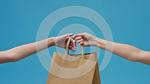 Young woman hand hold brown clear empty blank craft paper bag food for takeaway over blue background. Copy space for place a text