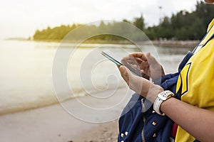 Young woman hand hold and touch screen smart phone on beach and