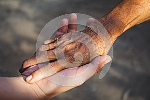 Young woman hand holding elderly person`s hand