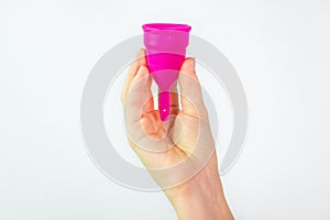 Young woman hand holding a pink menstrual cup