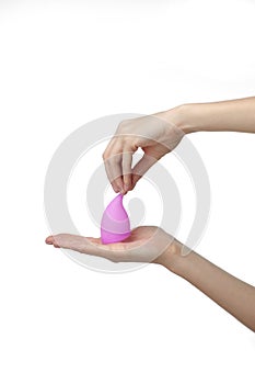 Young woman hand holding a pink menstrual cup - white background. Gynecology concept