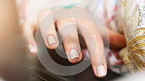 Young woman hand with manicure types on laptop touchpad