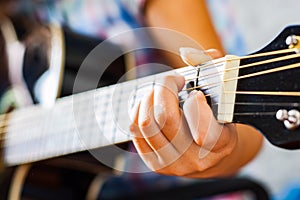 Young woman hand playing on black acoustic guitar