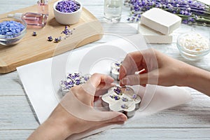 Young woman  handmade soap bar with lavender flowers on white wooden background, closeup