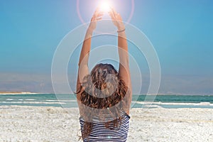 Young woman hands catching the energy of the sun. long-haired girl sits on the shore of the Dead Sea in Israel