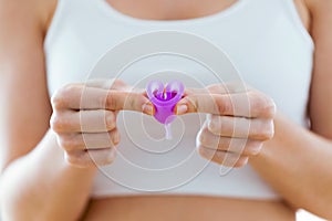 Young woman hands folding a menstrual cup.