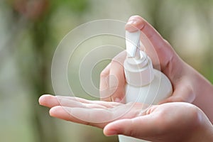 Young Woman hands holding body lotion bottle and using cream for treatment skin in winter time. photo