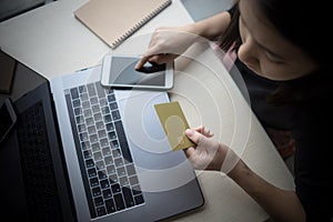 Young woman hands holding credit card using laptop computer and mobile smart phone Online shopping