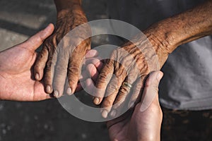 Young woman hands holding elderly person`s hands