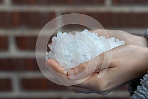 Young woman hands holding hailstones after a storm
