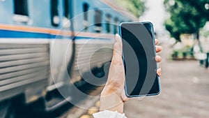 Young woman hands holding mobile at railway station for searching hotel room for booking and payment by internet cashless