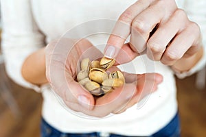 Young woman hands holding and picking up a pistachios nuts at home