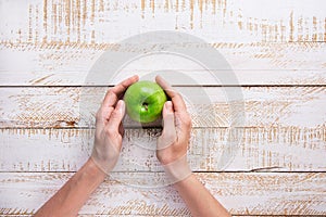 Young Woman Hands Holding Ripe Green Apple on White Plank Wood Background Tabletop. Flat Lay Top View Thanksgiving Harvest Autumn