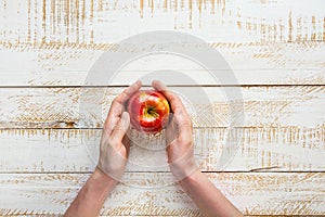 Young Woman Hands Holding Ripe Red Apple on White Plank Wood Background Tabletop.Flat Lay Top View Thanksgiving Harvest Autumn