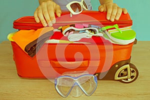 Young woman hands packing suitcase. Women`s clothes and accessories in red suitcase things prepared for travel