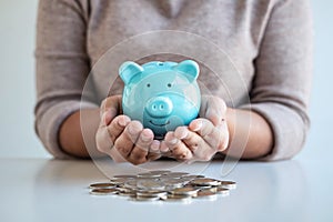 Young woman hands protection piggy bank and planning growing saving to strategy with pile coins for future plan fund of travel,