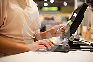 Young woman hands scaning, entering discount, sale on a receipt, touchscreen cash register, market shop