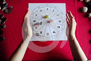 Young woman hands showing group of colorful crystal stones during tarot reading with red backgroundyoung woman hands showing group photo