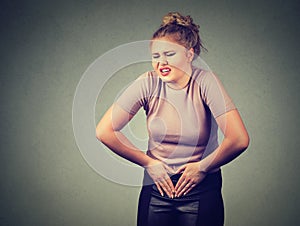 Young woman hands on stomach having bad aches pain. Food poisoning, influenza, cramps.