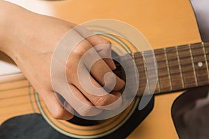 Young woman hands touching guitar chords