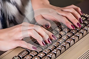 Female hands typing on old computer keyboard in office