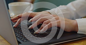 Young woman hands using laptop computer studying in cafe student drinking coffee typing email messages browsing online