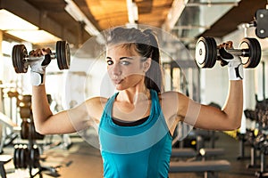 Young woman hang up hand weights in gym.