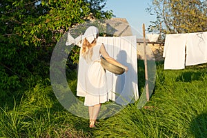 Young woman hanging laundry outdoors. Beautiful girl working in countryside
