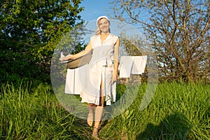 Young woman hanging laundry outdoors. Beautiful girl working in countryside