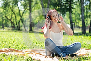 Young woman happens to have music in a summer park